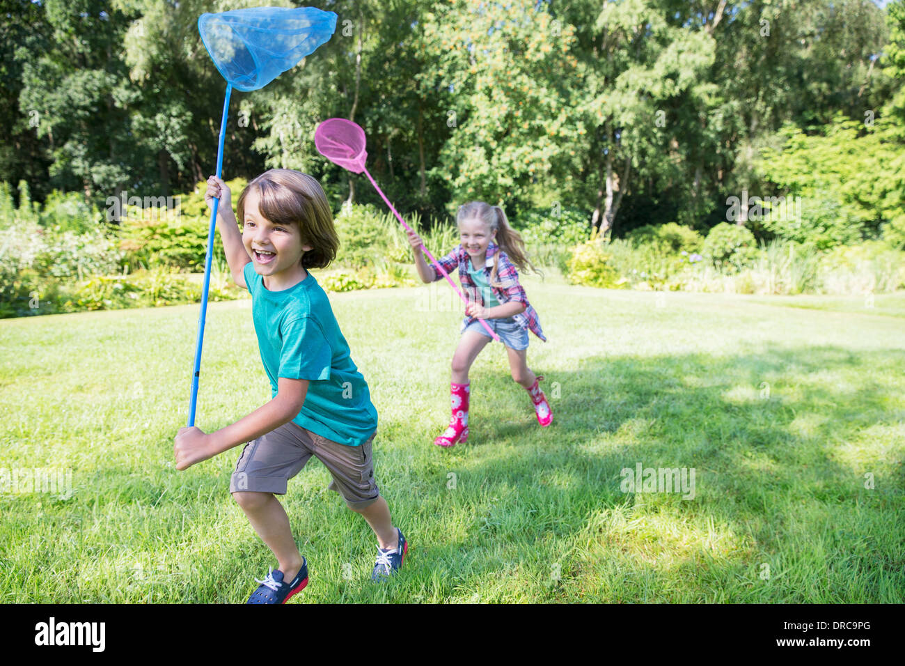 Boy and girl running with butterfly nets in grass Stock Photo Alamy