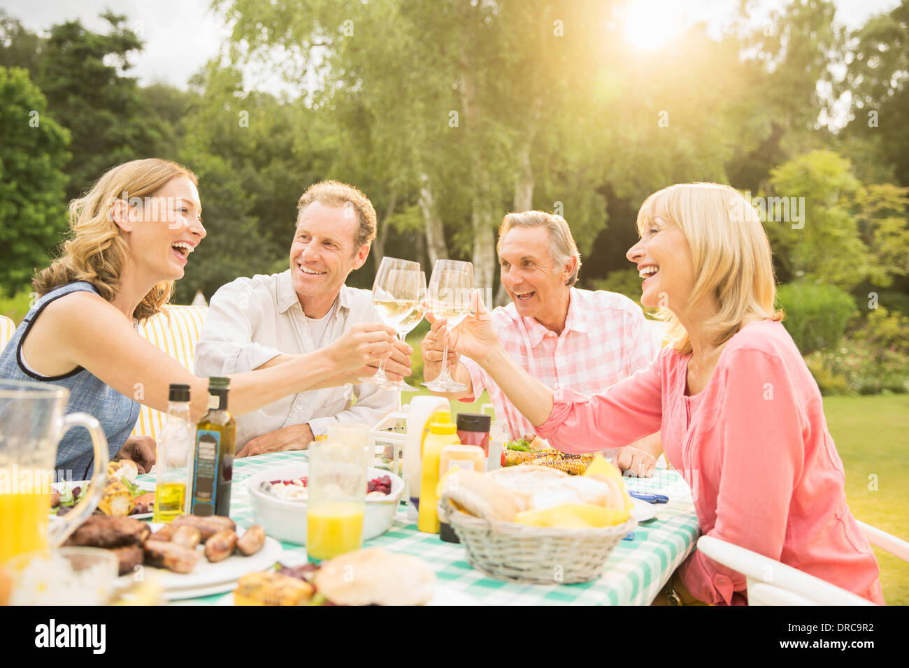 Couples toasting wine glasses at table in backyard Stock Photo