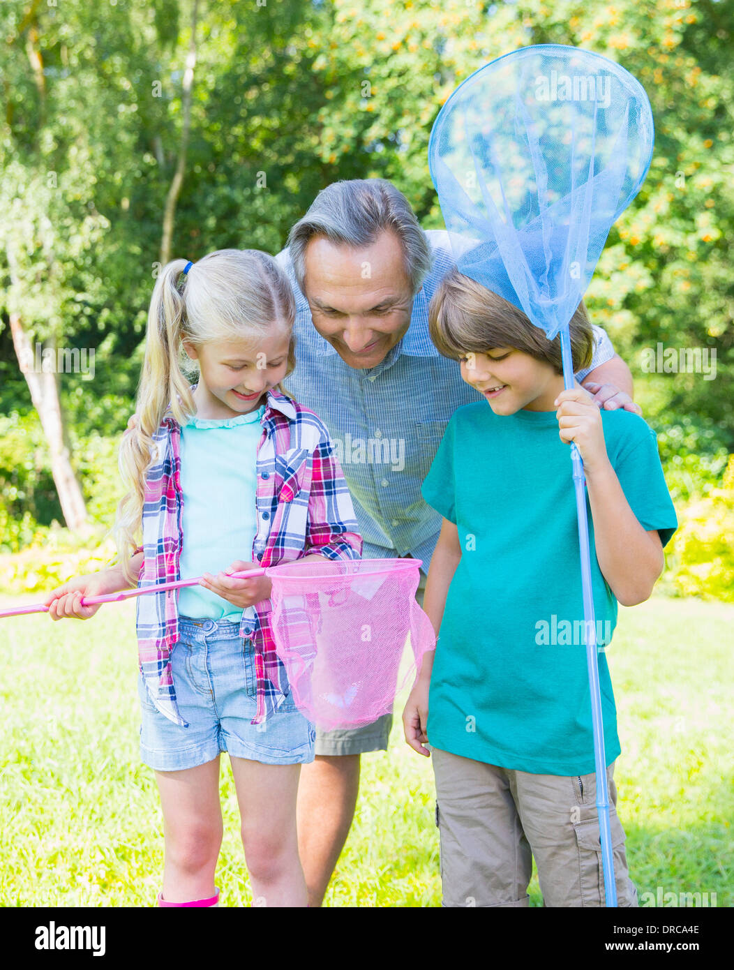 Grandfather and grandchildren looking at butterfly in net Stock Photo