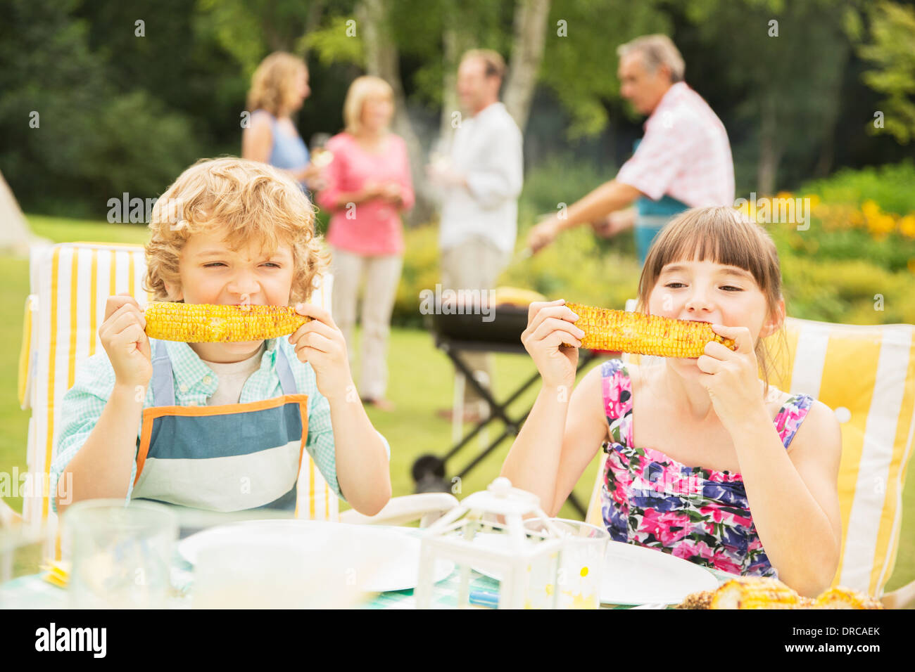 Children eating at table in backyard Stock Photo