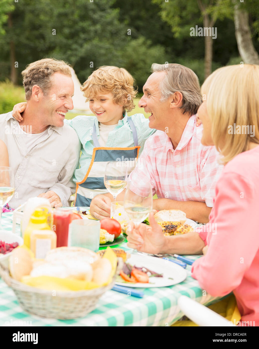 Family enjoying lunch at table in backyard Stock Photo