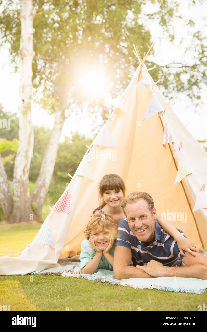 Father and children relaxing in teepee in backyard Stock Photo