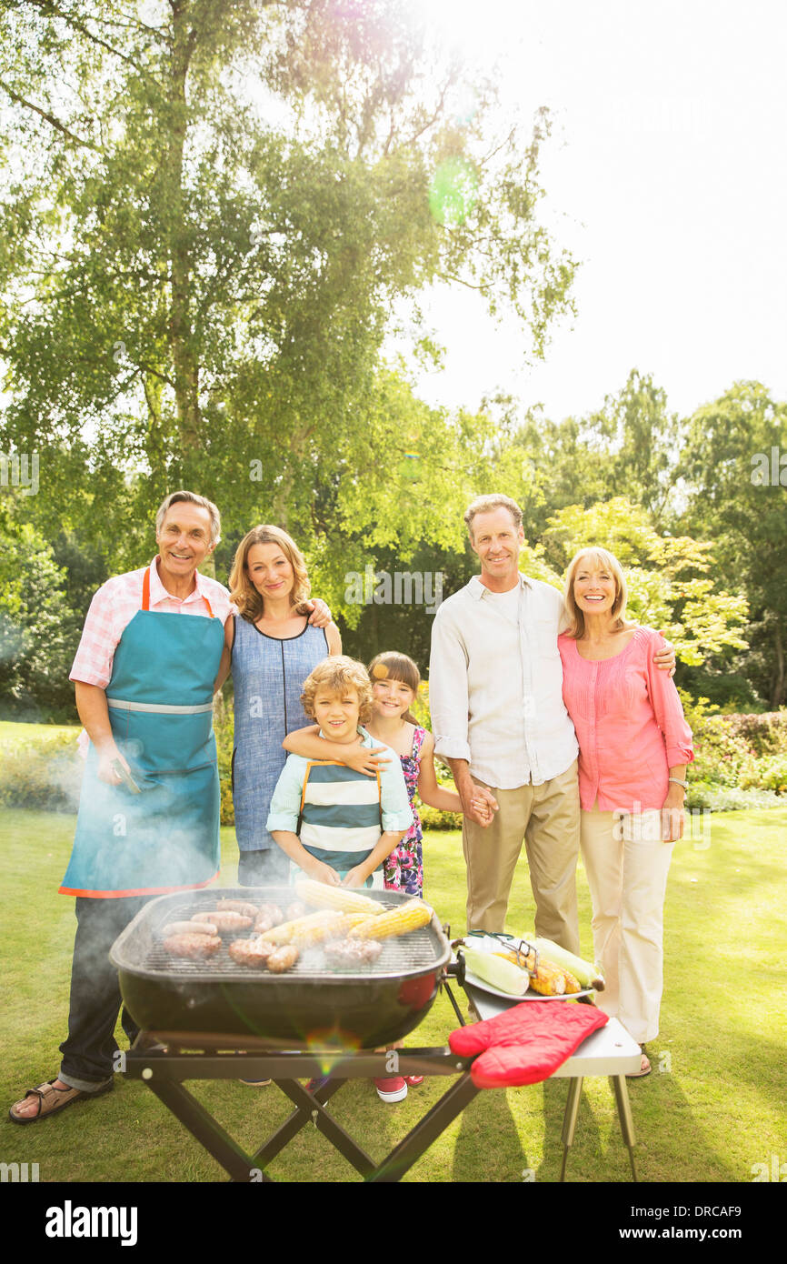 Multi-generation family standing at barbecue in backyard Stock Photo