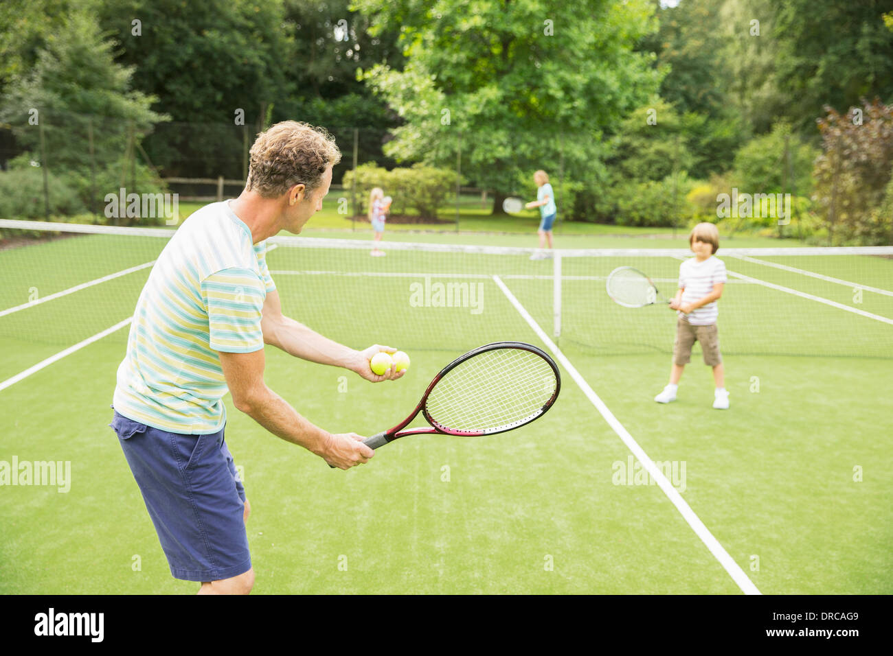 Family playing tennis on grass court Stock Photo