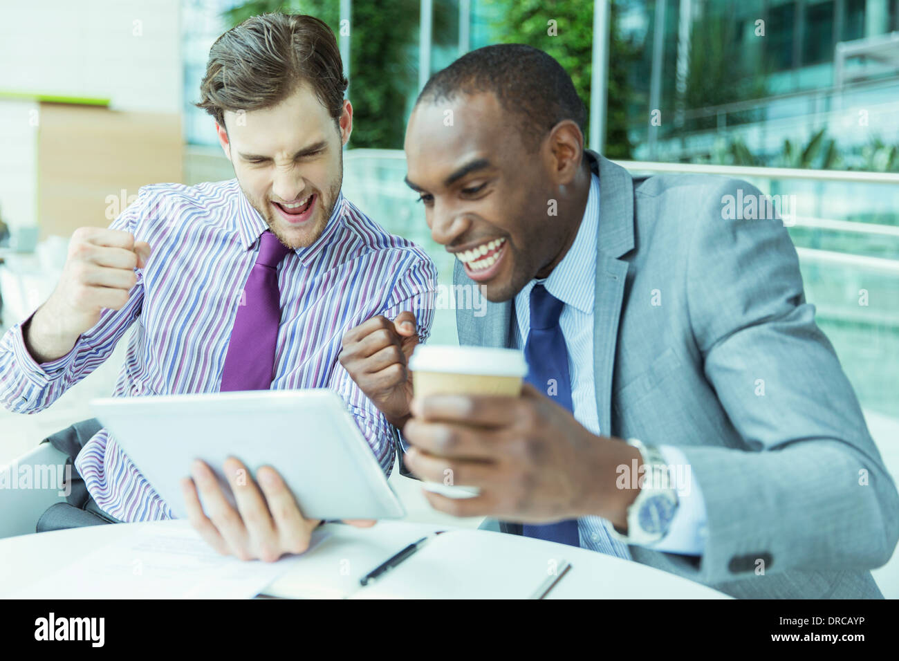 Businessmen cheering at digital tablet Stock Photo