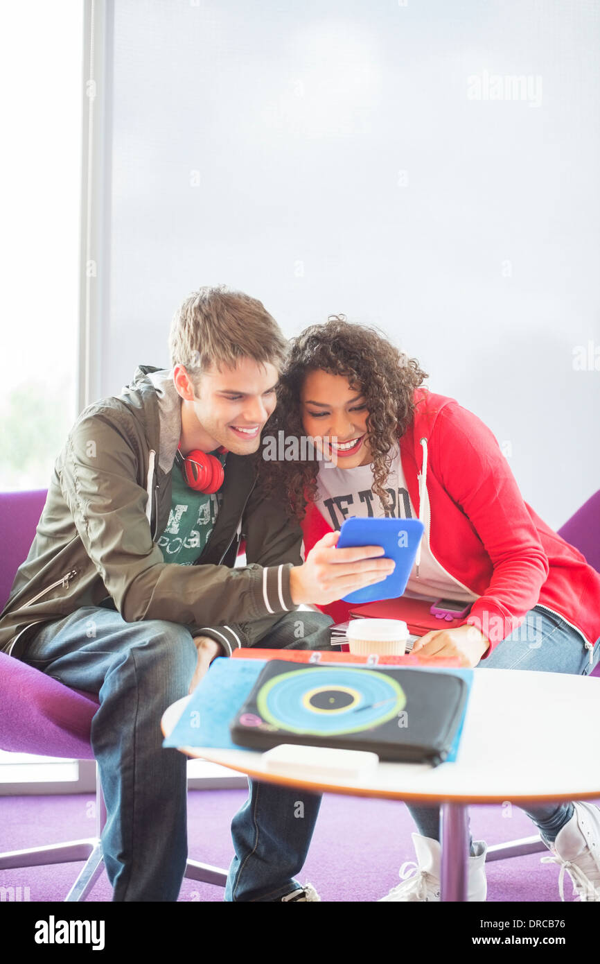 University students using digital tablet in lounge Stock Photo