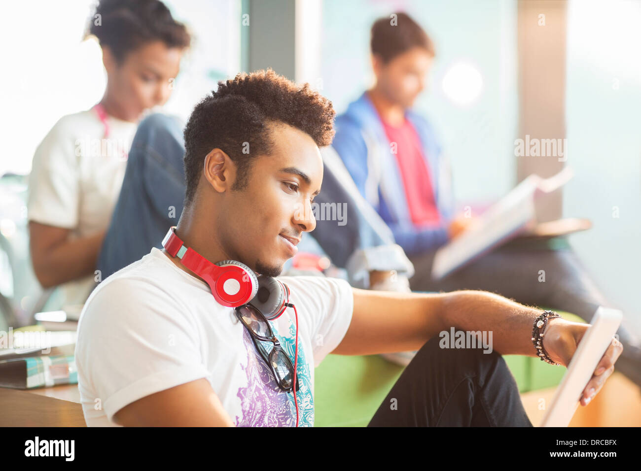 University student using digital tablet in lounge Stock Photo