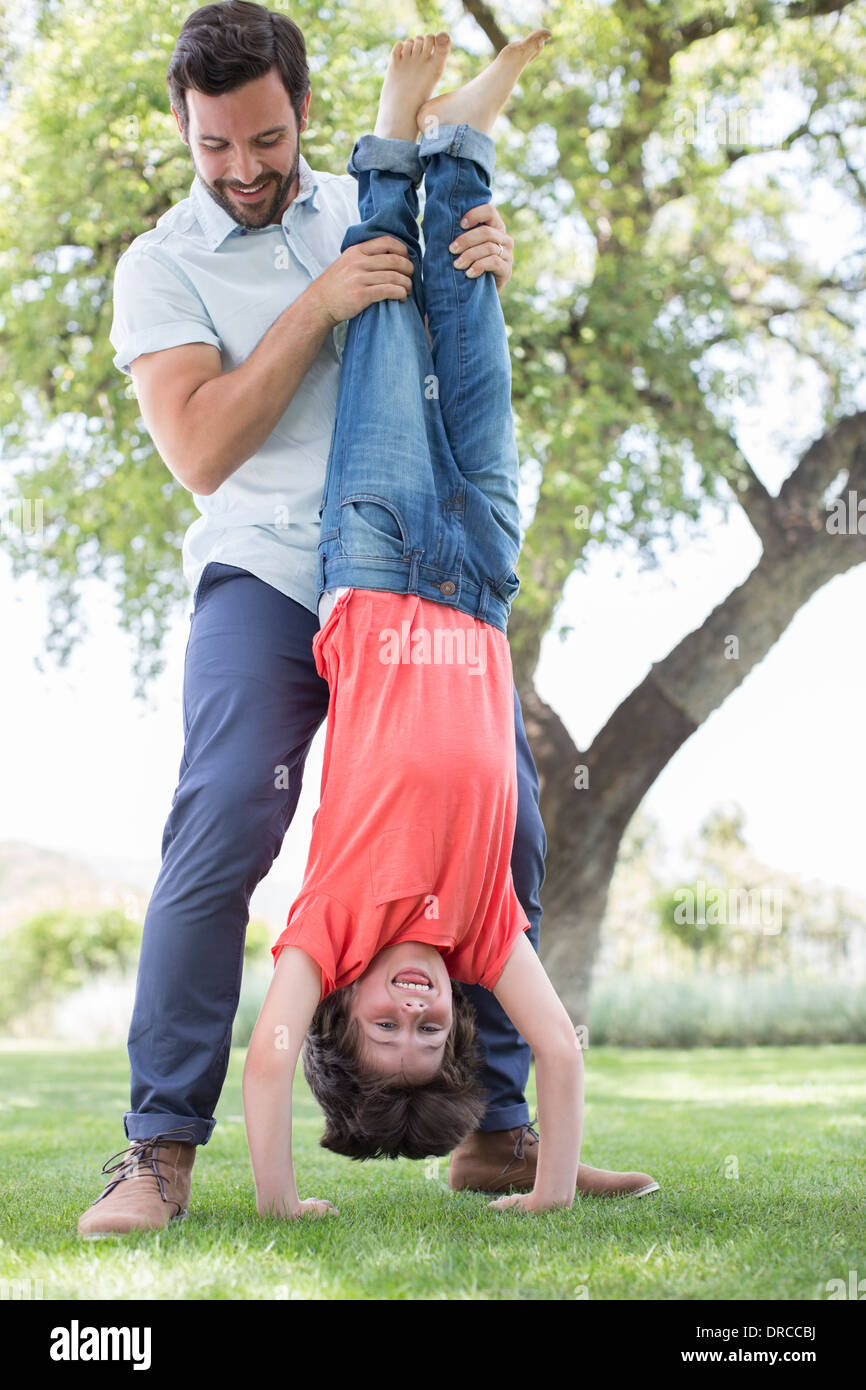 Father holding son upsidedown in backyard Stock Photo Alamy