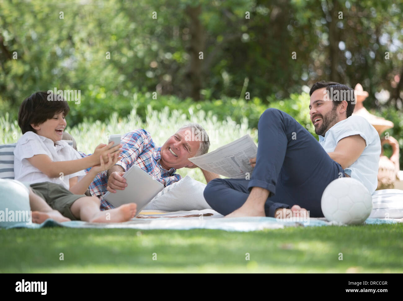 Multi-generation men relaxing on blanket in backyard Stock Photo