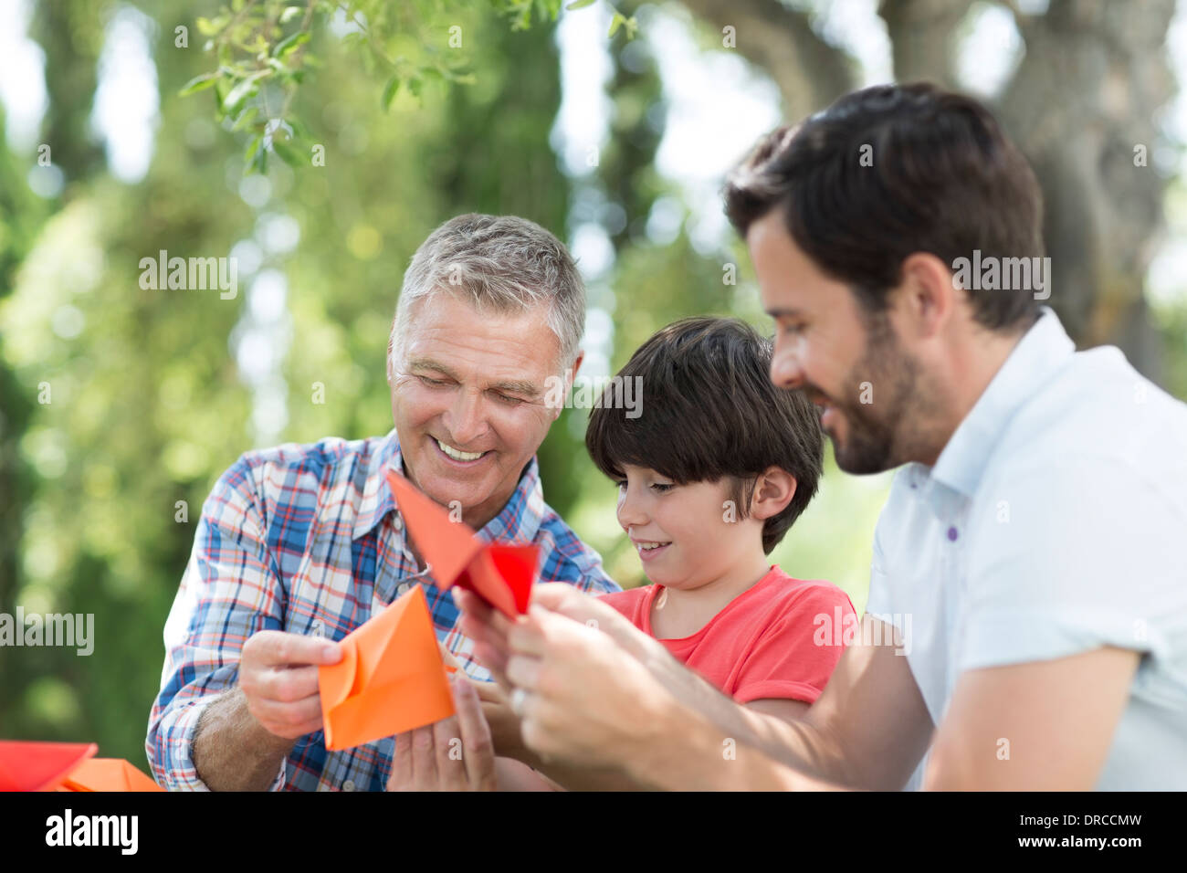 Multi-generation men making origami outdoors Stock Photo