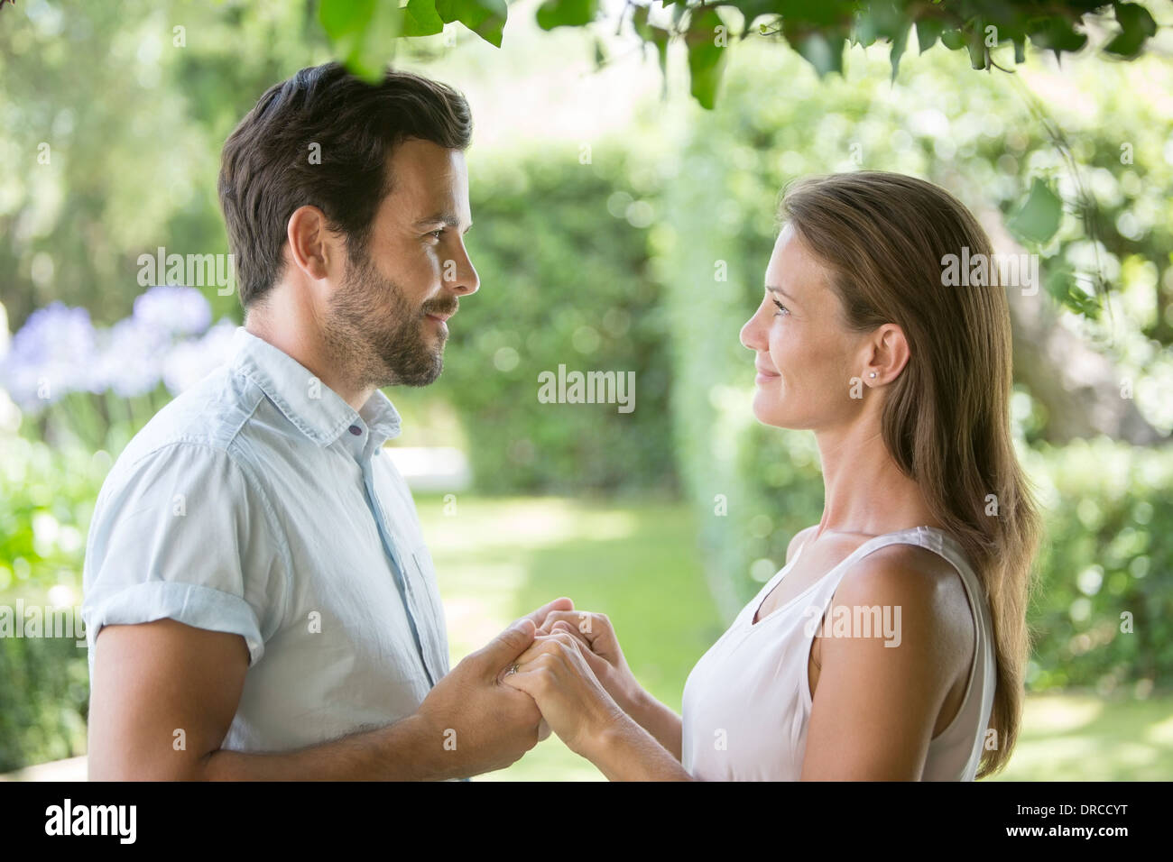Couple holding hands face to face in garden Stock Photo