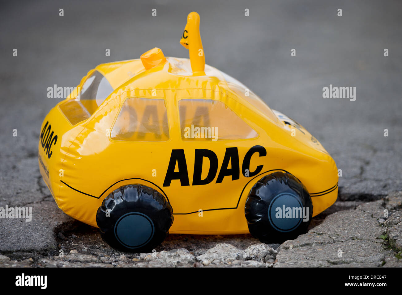 Solingen, Germany. 23rd Jan, 2014. ILLUSTRATION - An inflatable toy car with the logo of German automobile club ADAC sits in a pothole in Solingen, Germany, 23 January 2014. The tax payments to the ADAC are now coming under scrutiny after the manipulated figures in the ADAC election for Germany's favorite car. Photo: ROLF VENNENBERND/dpa/Alamy Live News Stock Photo