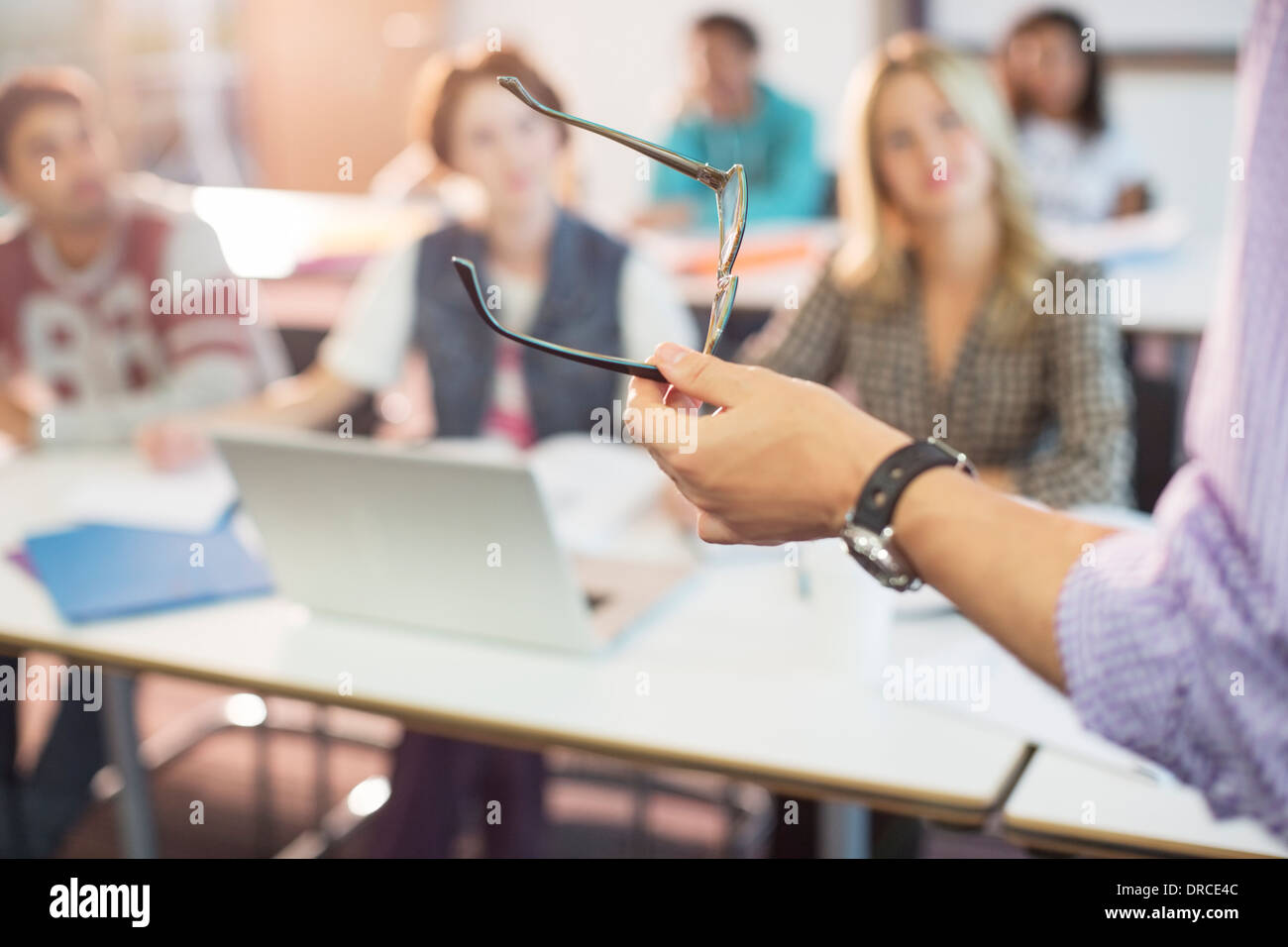 Professor gesturing with eyeglasses in classroom Stock Photo