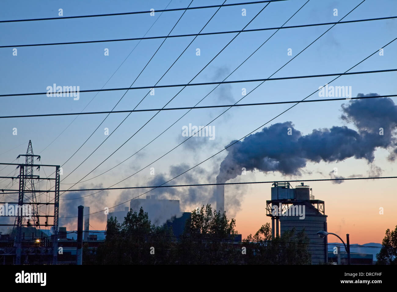 Silhouette of smoke emitting from factory at sunrise Stock Photo