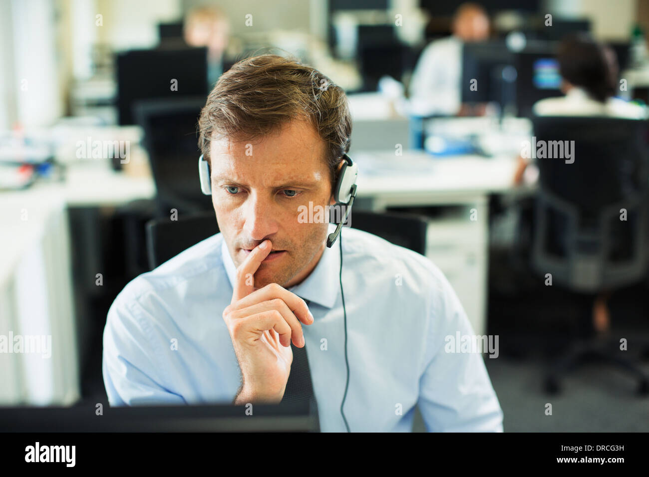 Businessman wearing headset in office Stock Photo