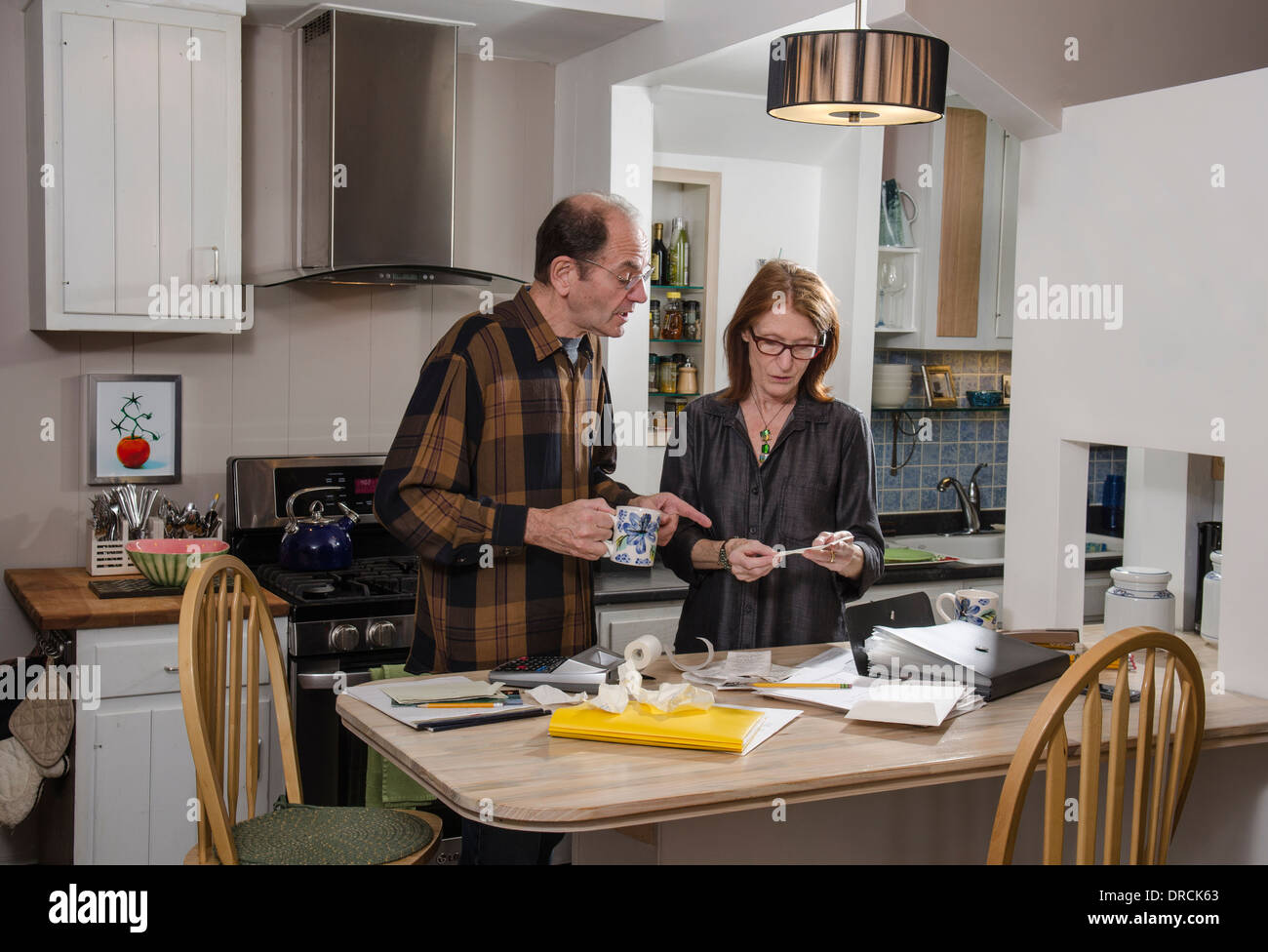 senior couple in kitchen with finances Stock Photo