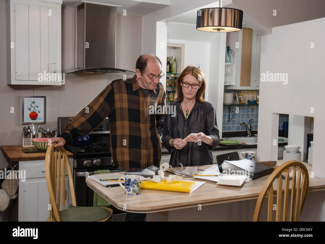 senior couple in kitchen with finances Stock Photo