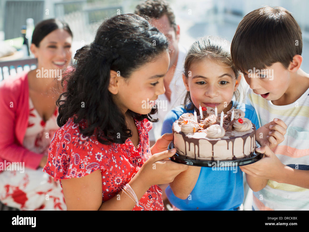 Children holding birthday cake outdoors Stock Photo
