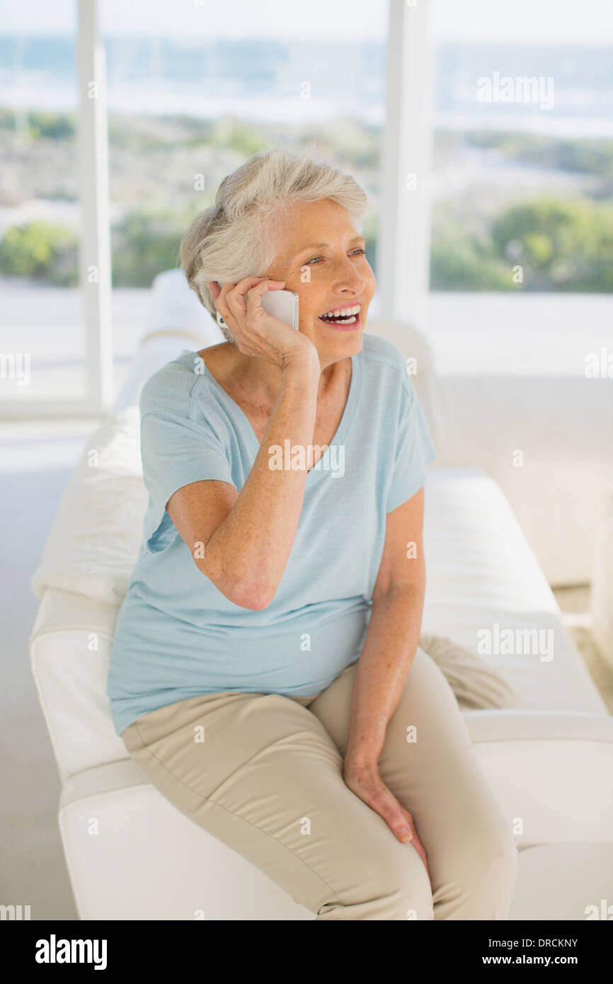 Senior woman talking on cell phone in living room Stock Photo