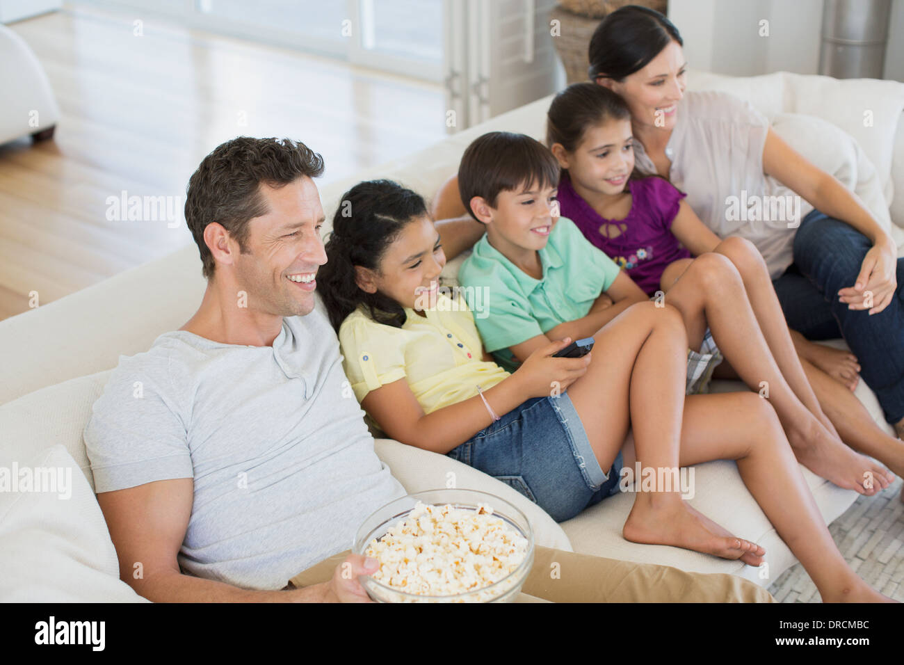 Family watching TV on sofa in living room Stock Photo