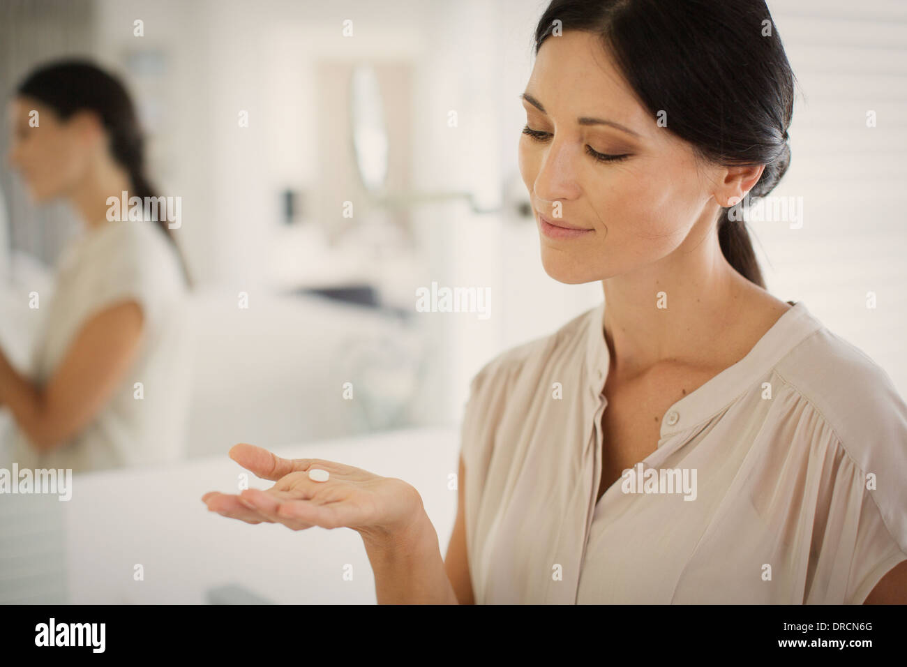 Woman taking pill in bathroom Stock Photo