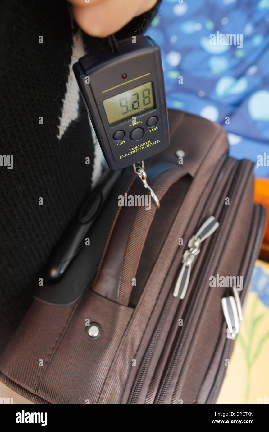 Weighing suitcase with digital scale for hand luggage on a flight Stock  Photo - Alamy