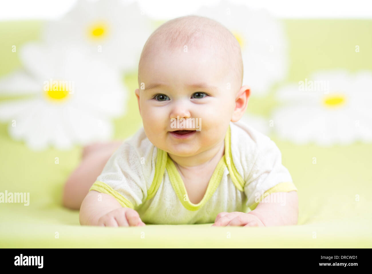 baby girl lying on green meadow among daisy Stock Photo