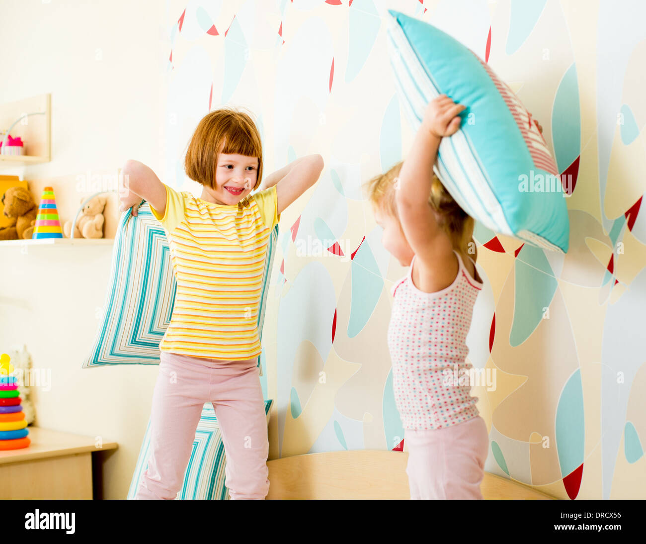kids sisters playing with pillows in the bedroom Stock Photo