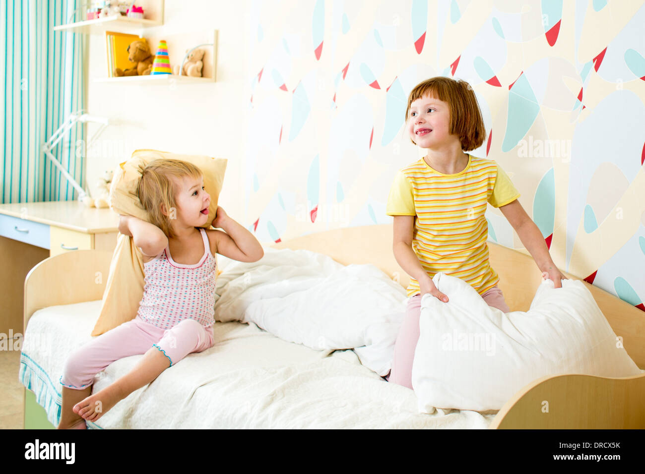 kids sisters playing on the bed indoors Stock Photo
