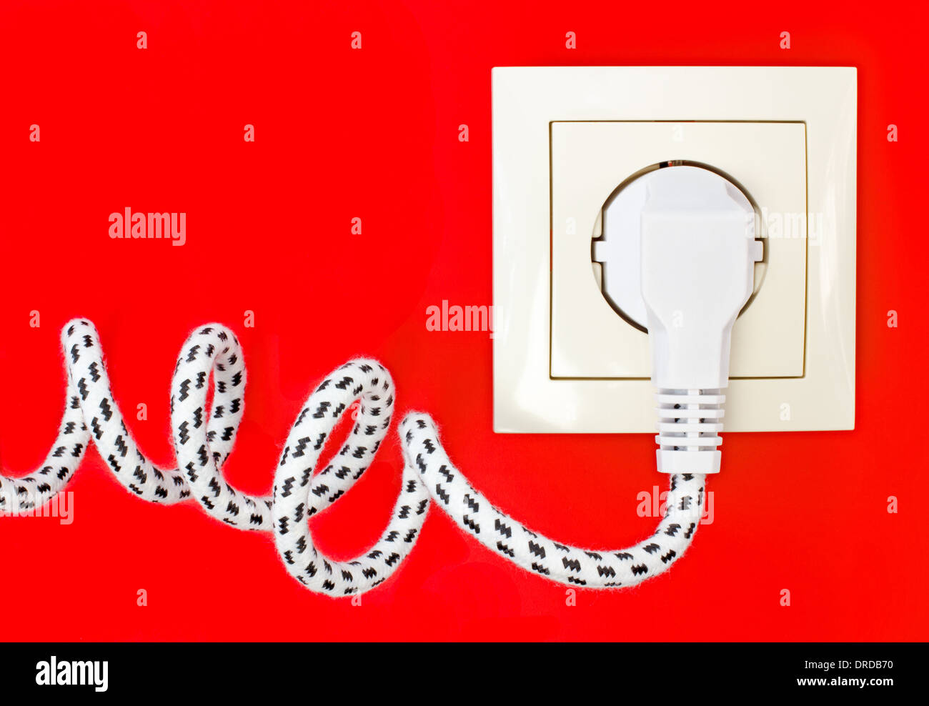 Textile power cord and power socket against a red background Stock Photo