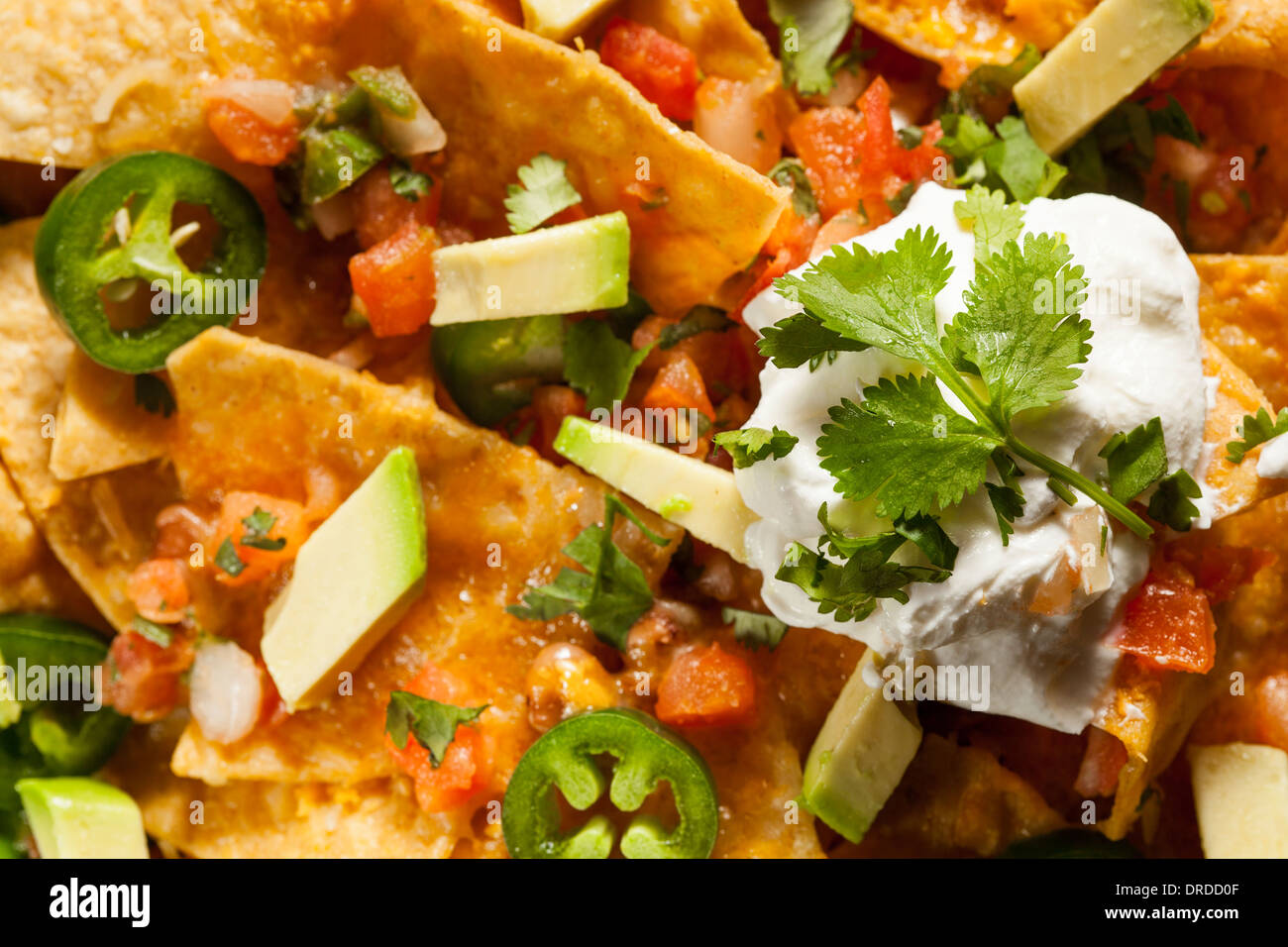 Homemade Unhealthy Nachos with Cheese, Sour Cream, and Vegetables Stock
