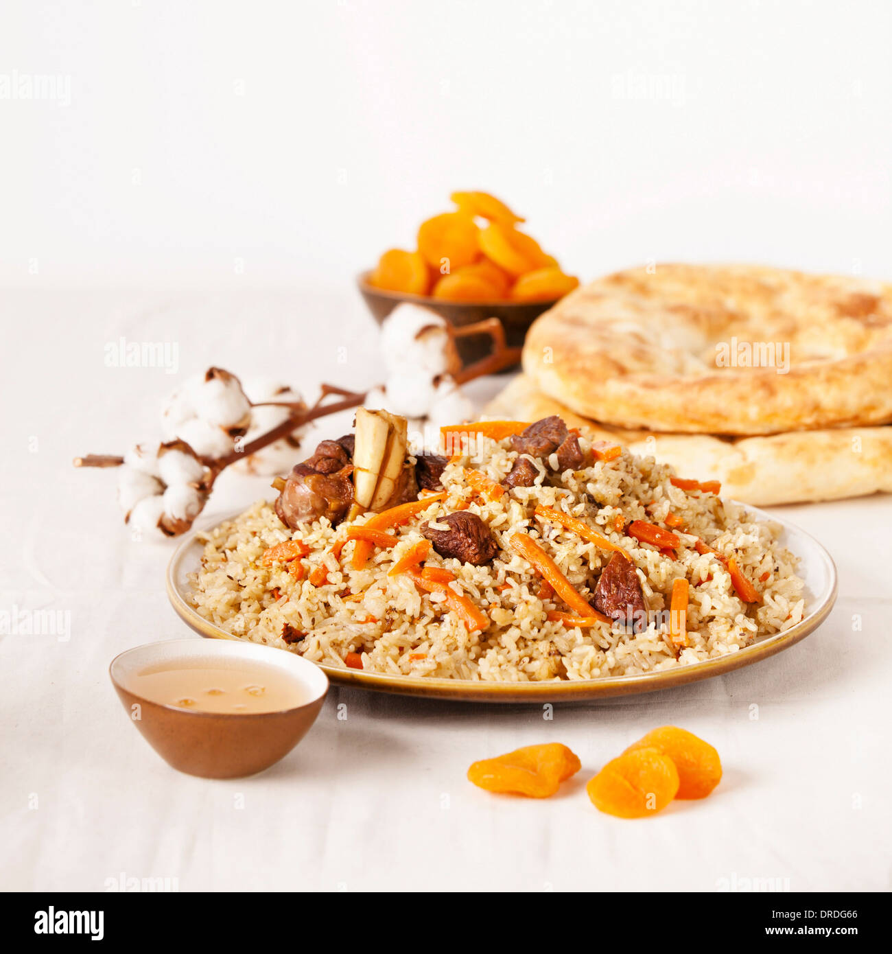 Uzbek national dish pilaf on plate with Uzbek bread and dried apricots Stock Photo