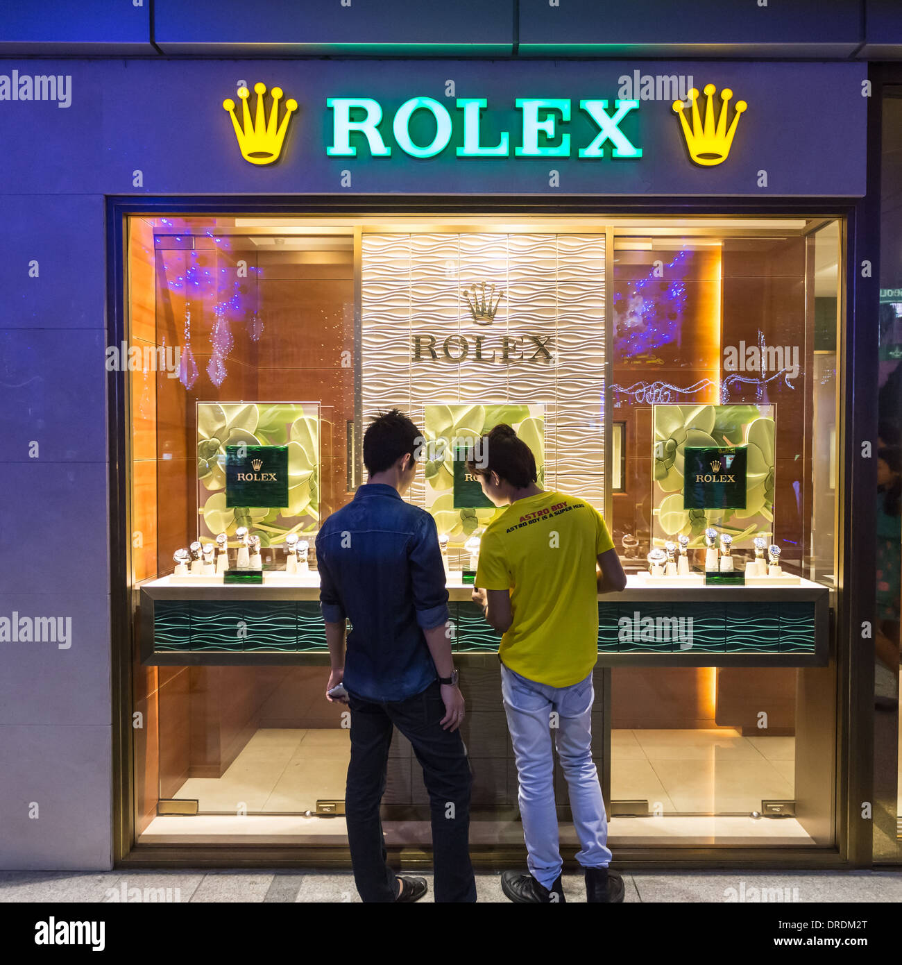 Two asian men looking at luxury Rolex watches in shop window Singapore. Stock Photo