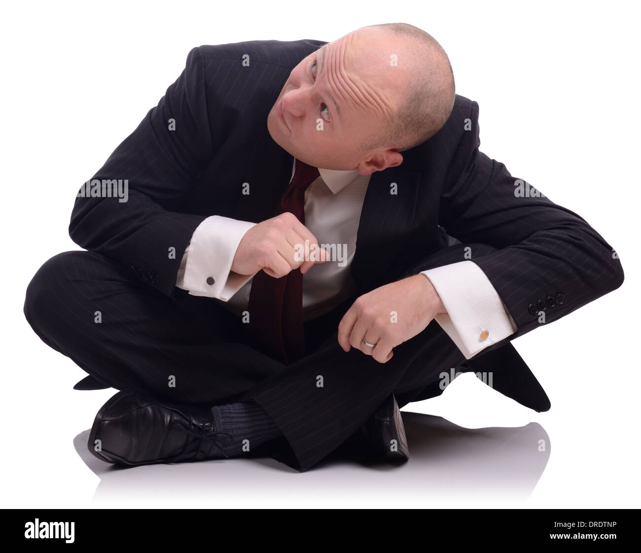 Businessman sat on the floor looking up and ducking down, isolated on a white background Stock Photo