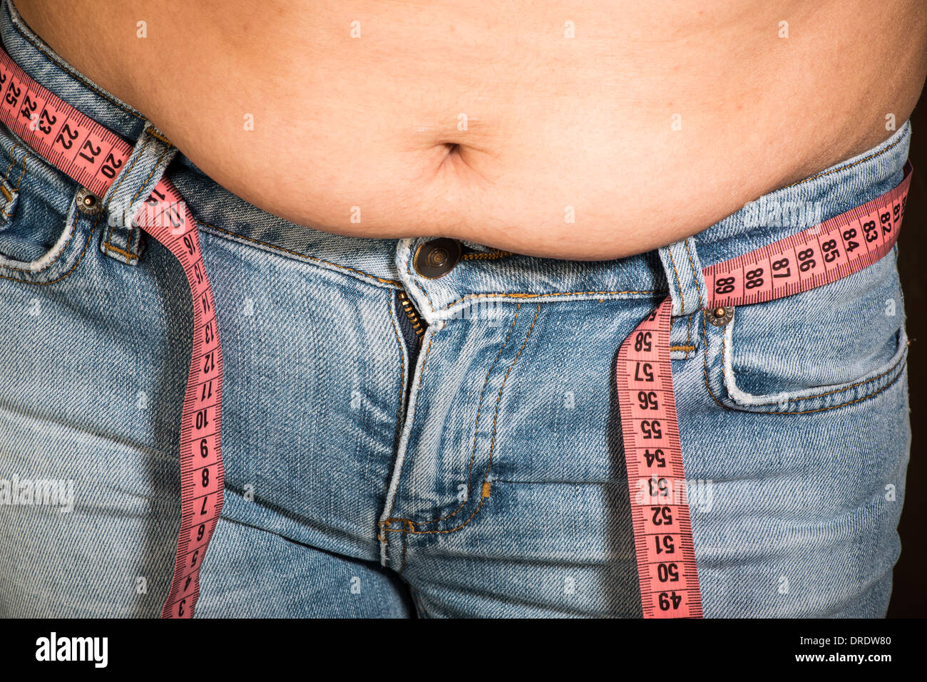 Woman showing fat belly. Pink tape measure Stock Photo - Alamy