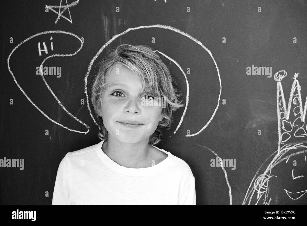 Boy standing in front of chalkboard wall, black and white Stock Photo