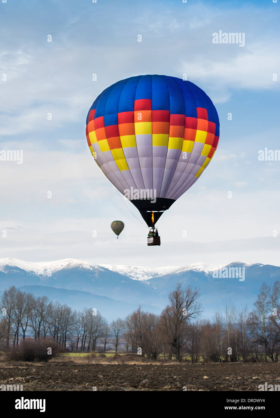Multicolored Balloon in the blue cloudy sky. Mountain background Stock Photo