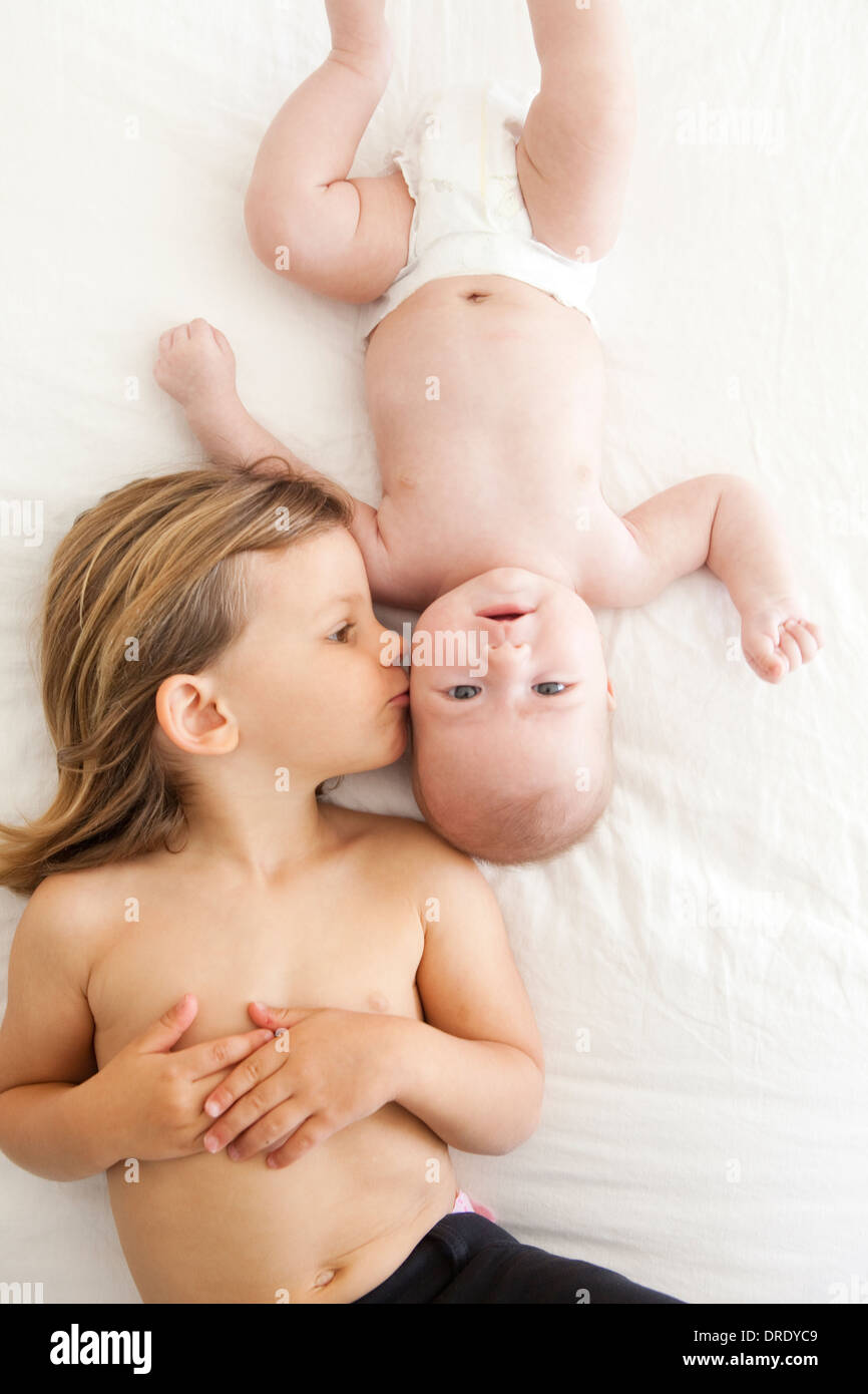 Sister kissing her younger sibling Stock Photo