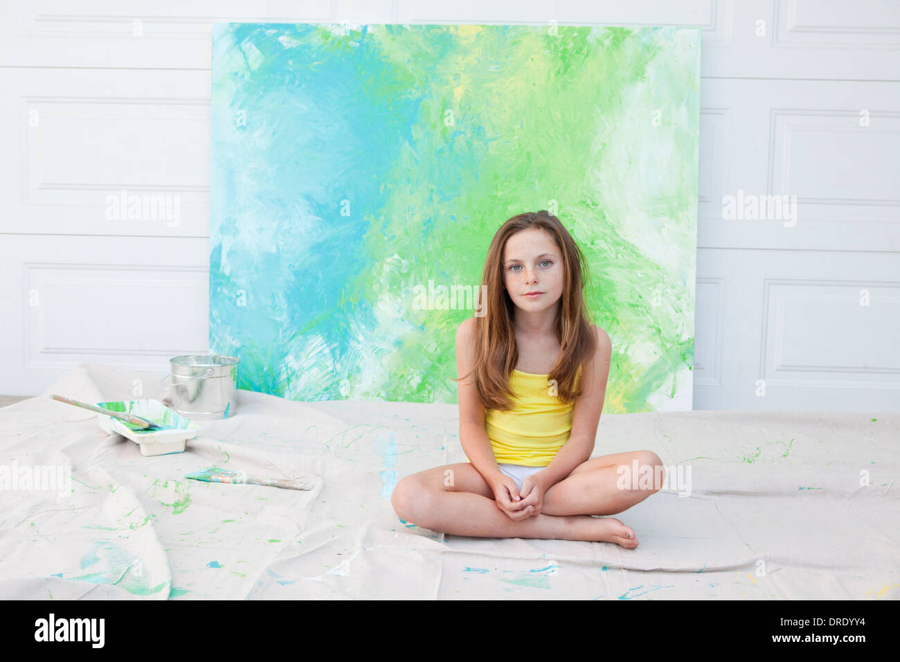 Young girl sitting in front of colorful blue and green painting Stock Photo