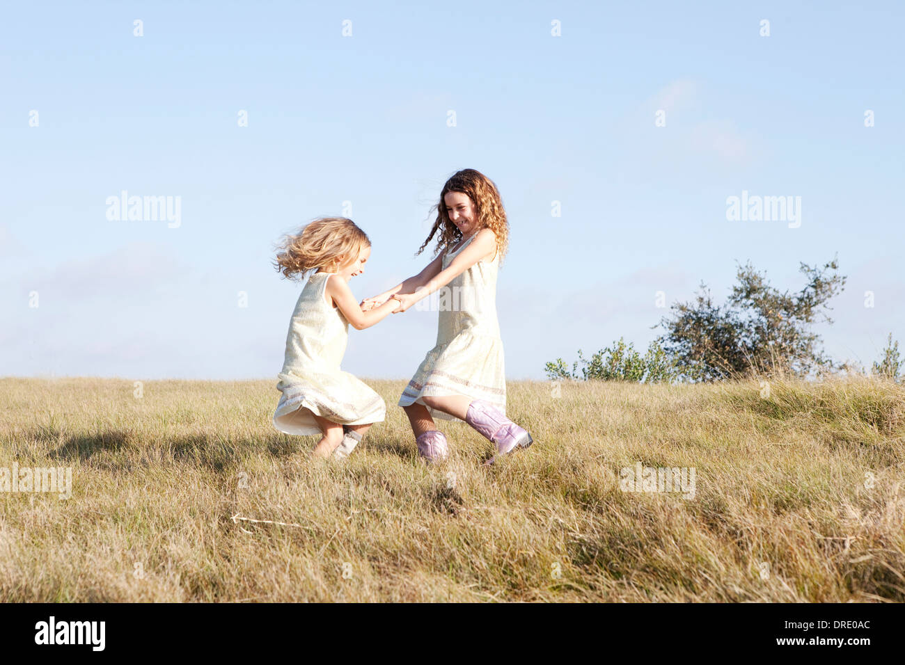 Sisters in dresses standing in field Stock Photo