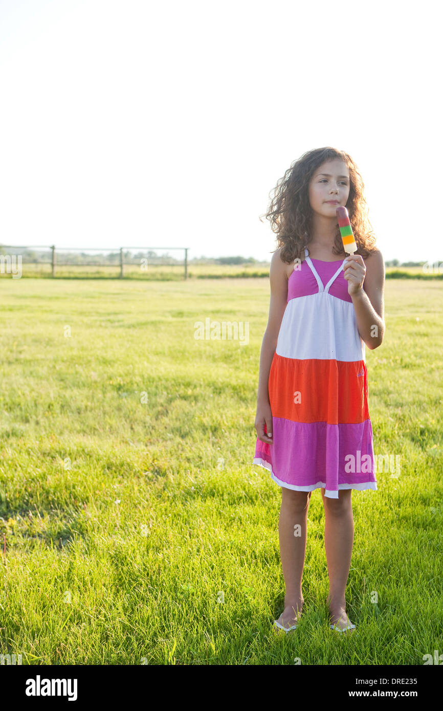 Girl eating a popsicle in the field Stock Photo