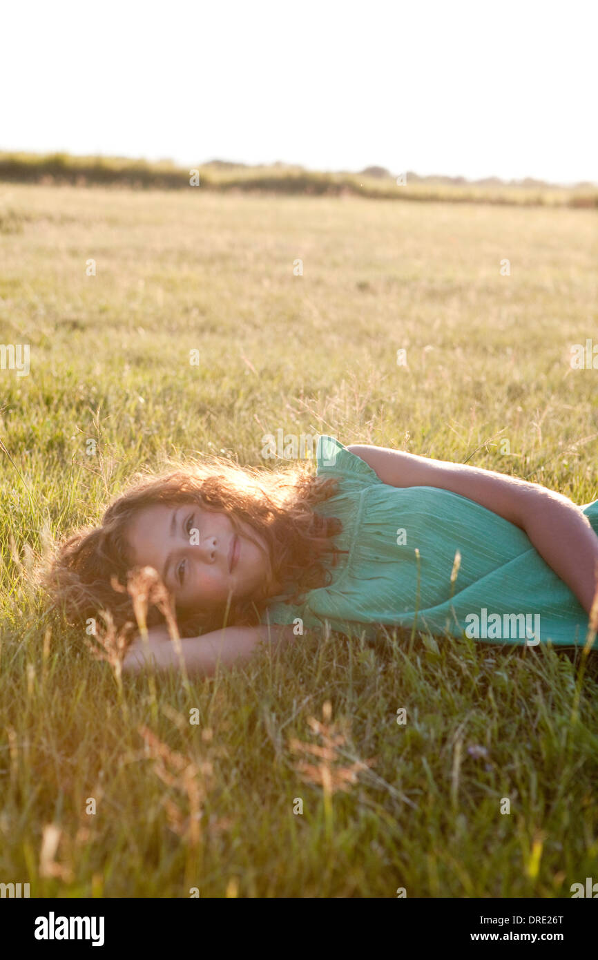 Girl lying on grassy hill Stock Photo