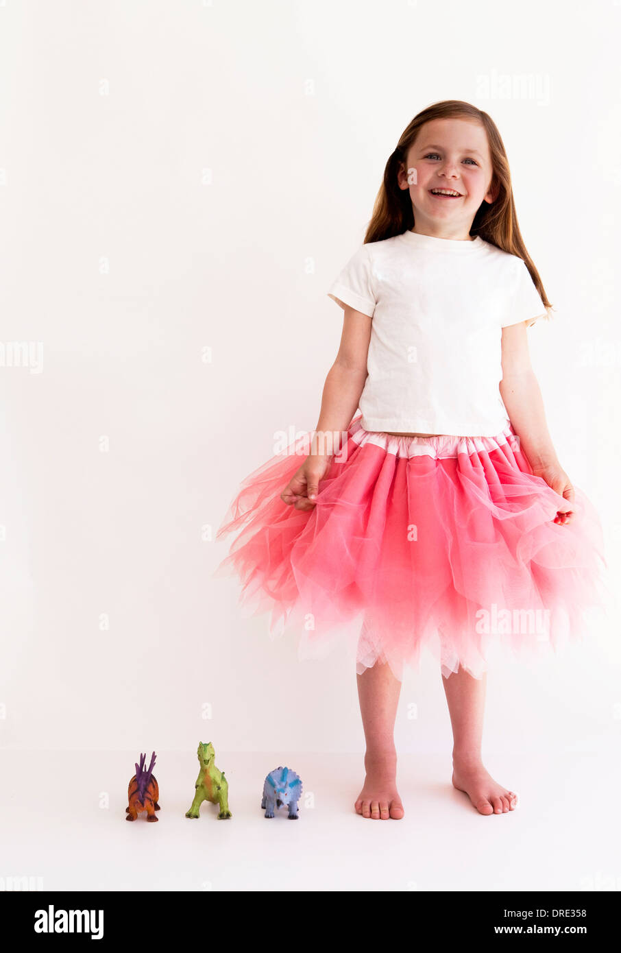 Girl in tutu with toy dinosaurs Stock Photo
