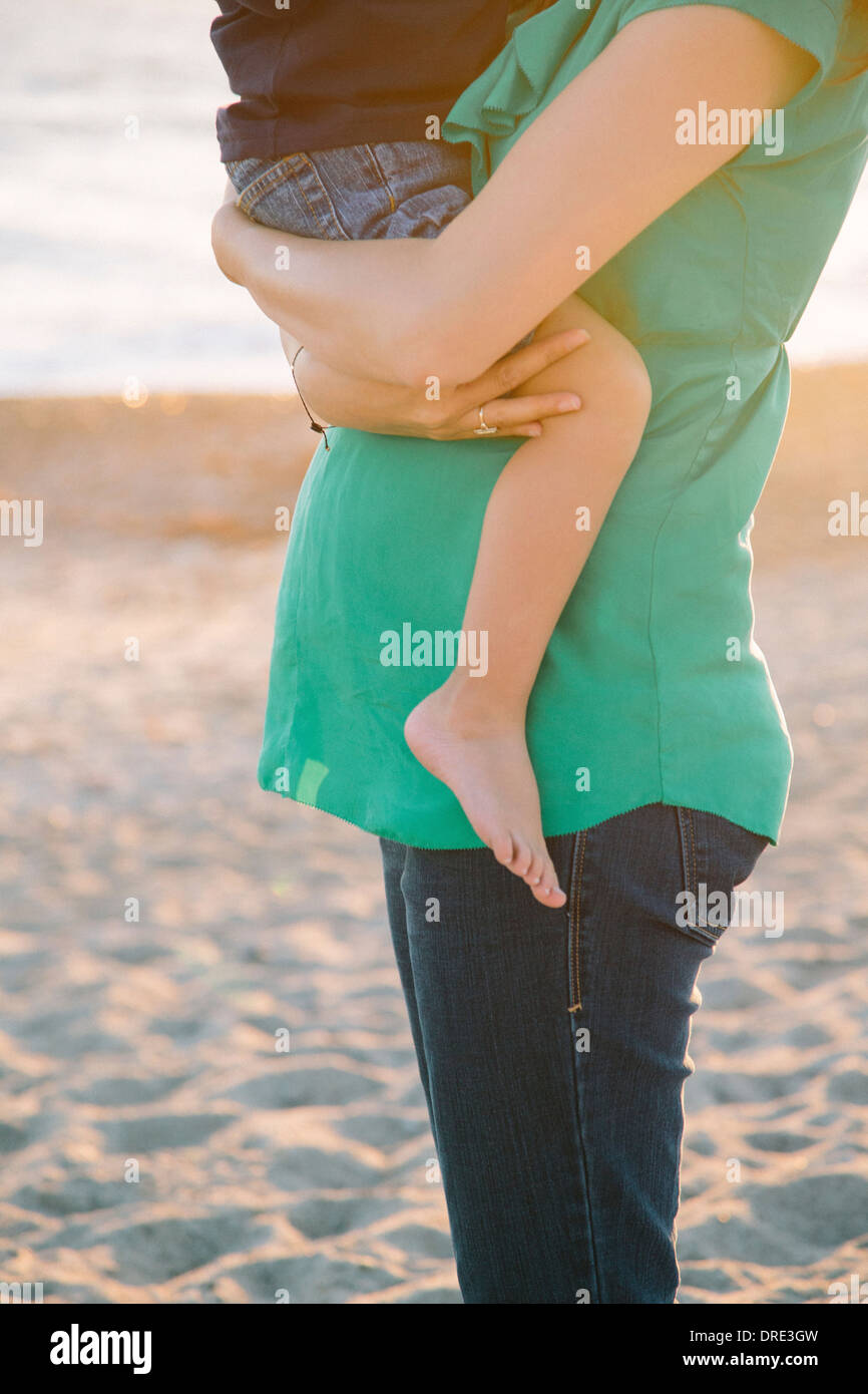 Pregnant woman holding boy on beach Stock Photo