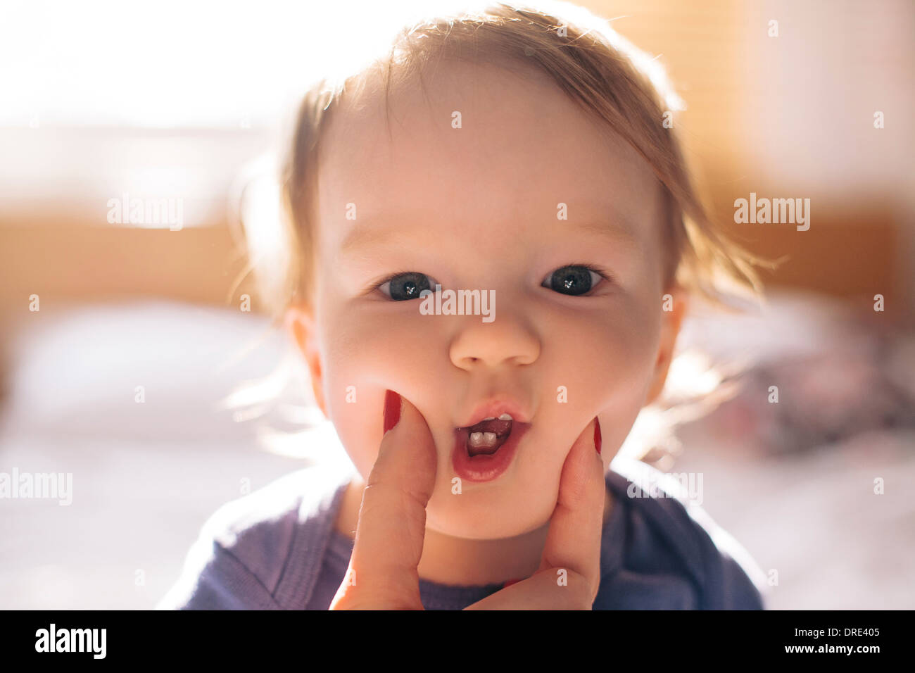 Pinching the cheeks of cute baby Stock Photo