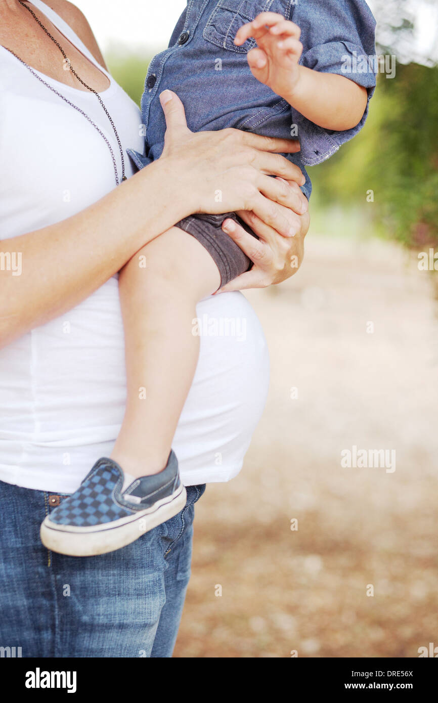 Pregnant mom holding young boy on baby bump Stock Photo