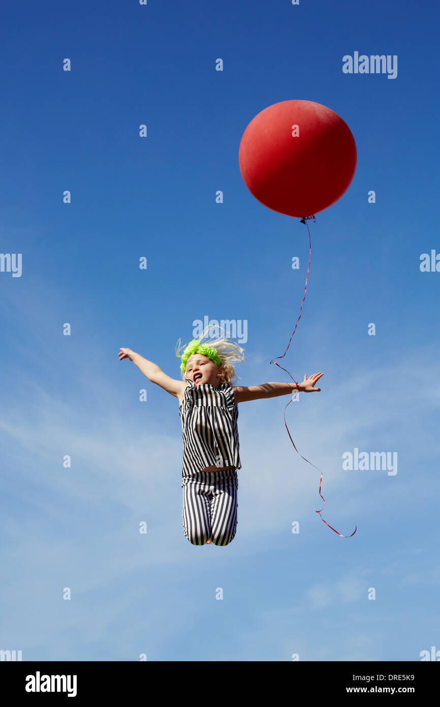girl jumping in the air with a red balloon Stock Photo