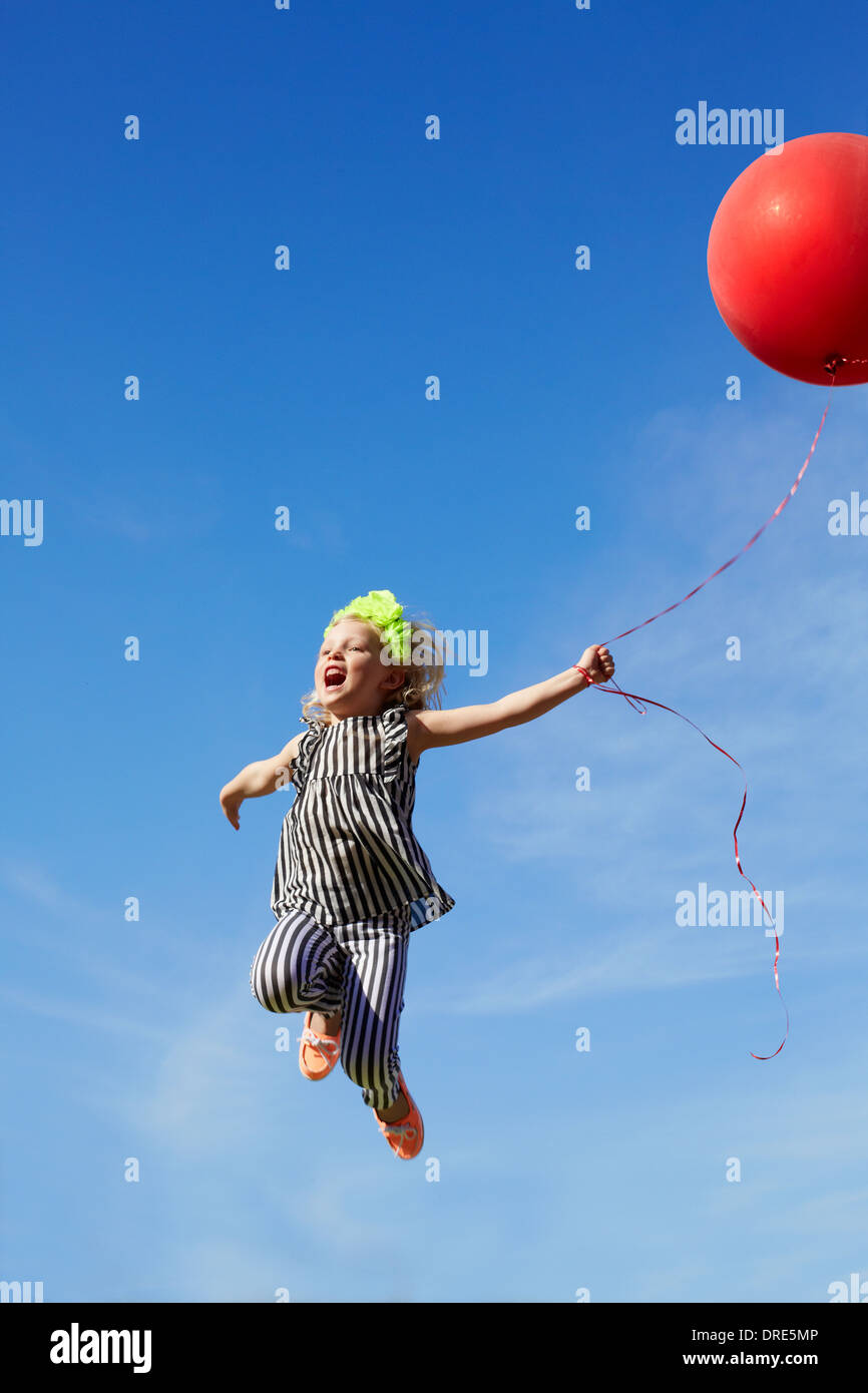 girl jumping in the air with a red balloon Stock Photo