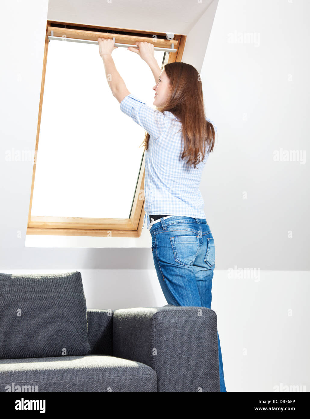 Young woman opens window at home Stock Photo