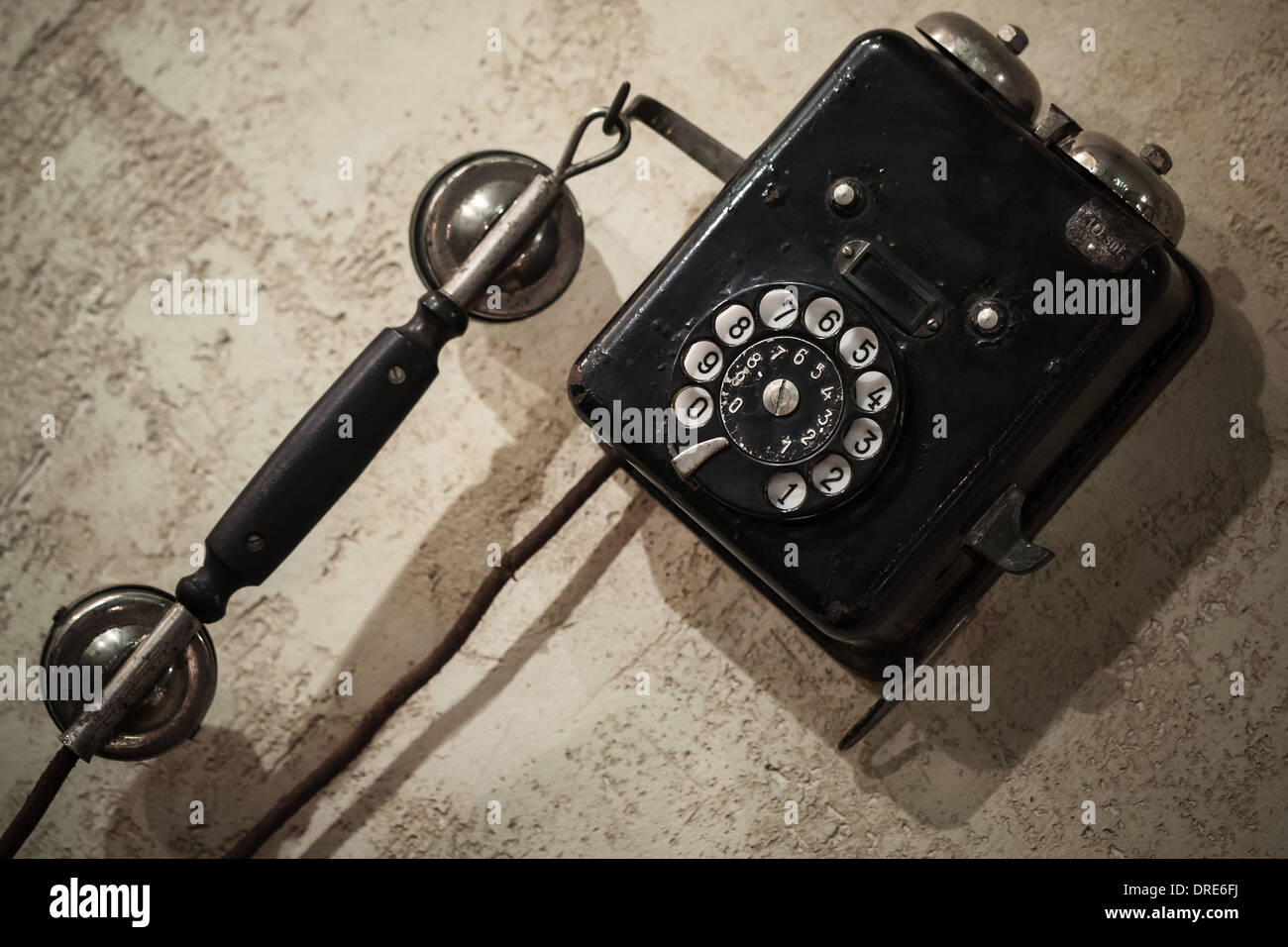 Vintage black phone hanging on old gray concrete wall Stock Photo